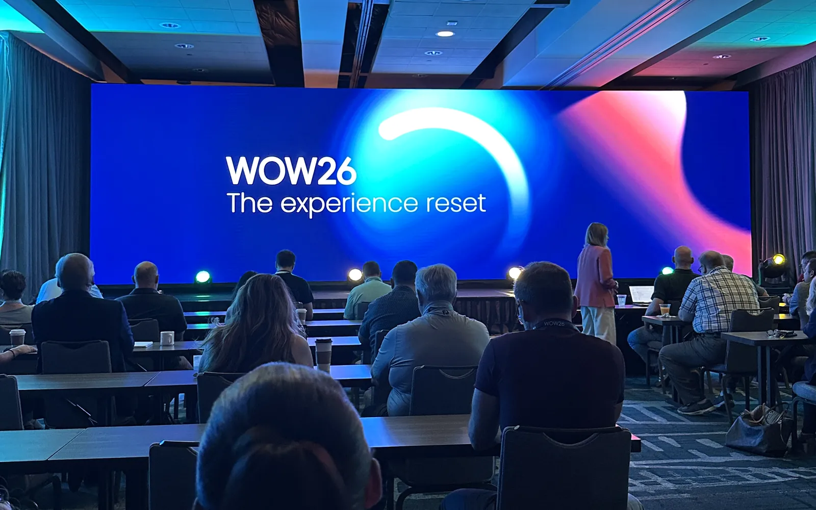 Attendees seated in the WOW26 keynote room in Scottsdale, facing a wide stage screen that reads WOW26, The experience reset.